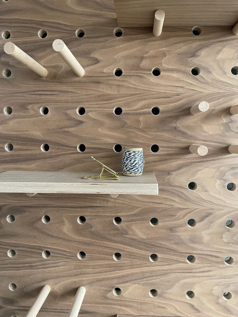 Walnut veneer birch plywood pegboard by kreisdesign with shelves and pegs that are fitted with pegs to slot into the pegboard holes