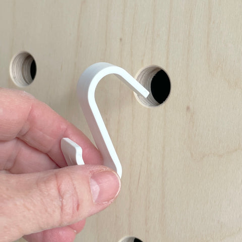 Detail of white hook that fits into the pegboard to hang the basket