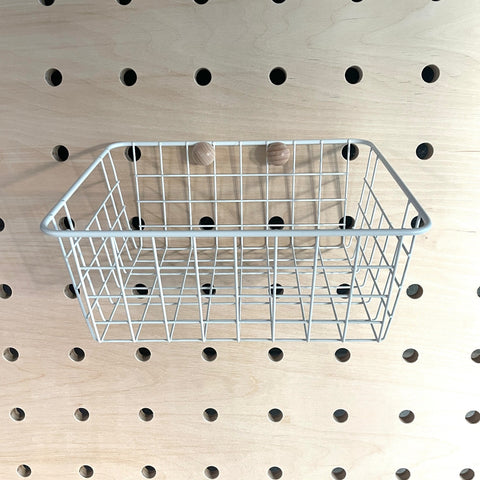 white wire basket for added storage to wooden pegboards to hang of pegs