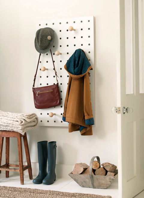 large white pegboard birch plywood in white by kreisdesign shown in a hallway with hat bag coat hanging on pegboard
