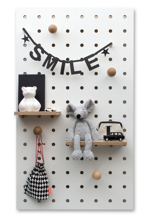 large white wooden pegboard with peg hooks and shelves in kids room