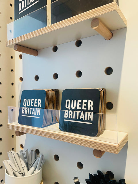 white display shelves with acrylic clear front to lean coasters or greeting cards - for kreisdesign pegboards. Here shown in Queer Britain store London