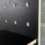 edge detail of black painted wooden pegboard by Kreisdesign showing the layers of the birch plywood