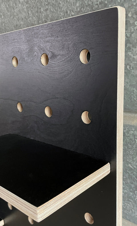 edge detail of black painted wooden pegboard by Kreisdesign showing the layers of the birch plywood