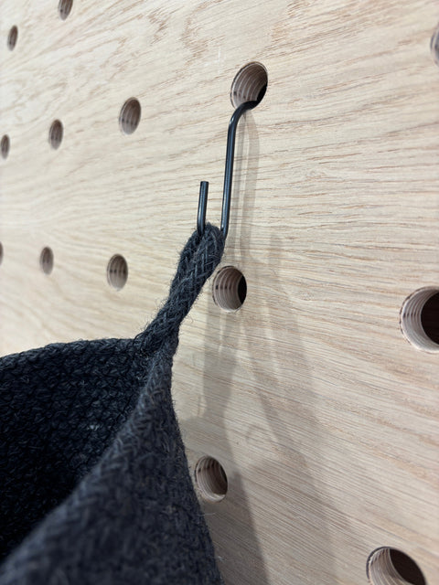 black hanging basket hung from black hook on kreisdesign pegboard