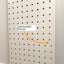 Pegboard with misaligned holes labeled on a white wall.