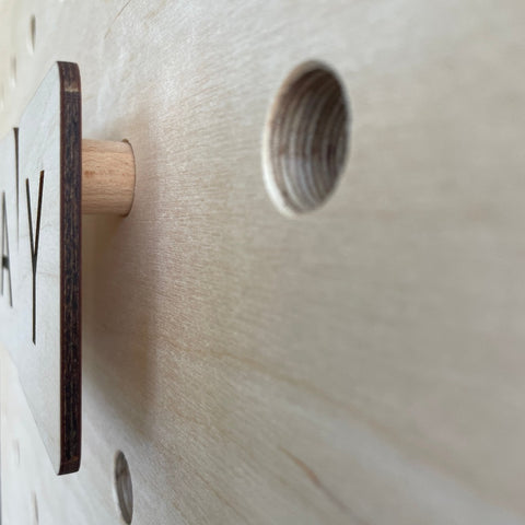 detail of wooden letters for pegboard with peg stuck into hole