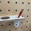 cup holder shelf with pencil on pegboard wood