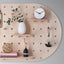 detail of large oval shaped wood pegboard with shelves and hooks made by kreisdesign