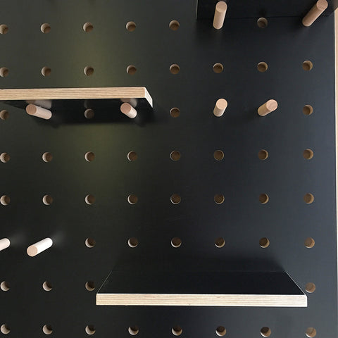 large black pegboard with shelves and pegs made from painted birch plywood