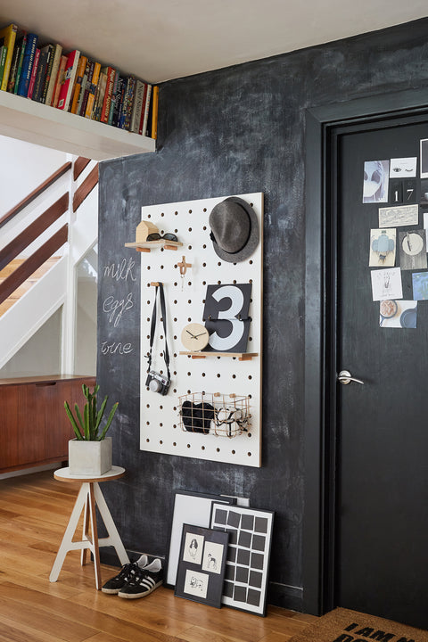 large wood pegboard in white by kreisdesign in hallway with shelves and pegs