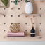 large oval shaped wood pegboard with shelves and hooks made by kreisdesign