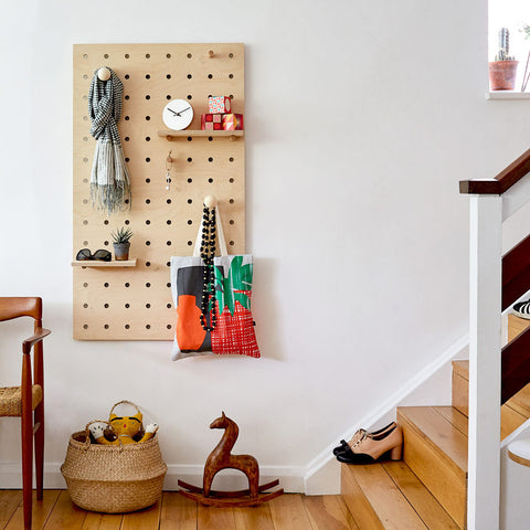 Large wooden pegboard coat rack with pegs and shelves in plywood